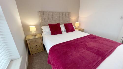 a bedroom with a large white bed with red pillows at Friars House, Stafford by BELL Apartments in Stafford