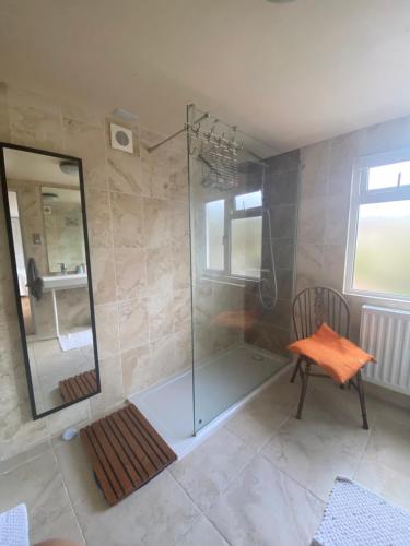 a bathroom with a shower and a chair and a mirror at Zen Cottage, Cheltenham in Cheltenham