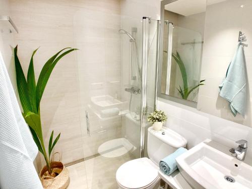 a white bathroom with a toilet and a sink at La Casa del Jardin. Menorca in Punta Grossa