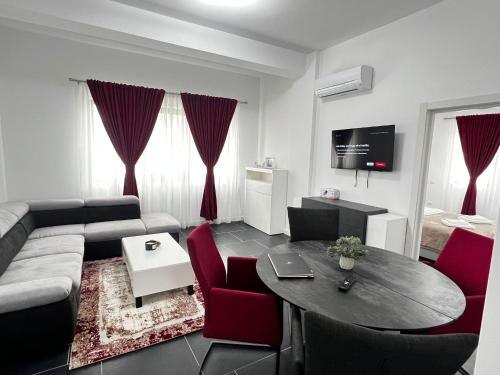 a living room with a couch and a table and red chairs at Cozy Aparthotel - Central City Suceava in Suceava