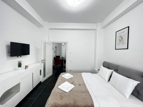 a white bedroom with a bed and a couch at Cozy Aparthotel - Central City Suceava in Suceava