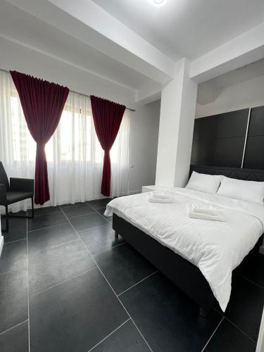 a bedroom with a large bed with red curtains at Cozy Aparthotel - Central City Suceava in Suceava