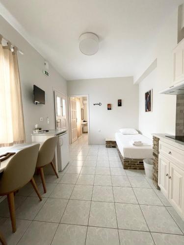 a white kitchen with a bed and a table at Manto Apartments in Tinos Town