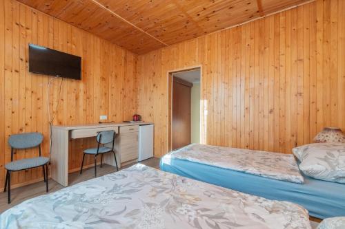 a room with two beds and a desk and a television at Holiday Ozon in Sztutowo