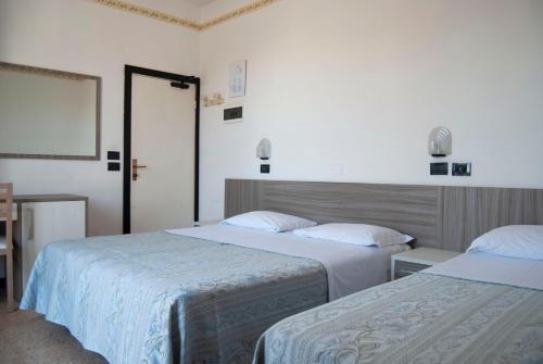 a bedroom with two beds with white sheets at Hotel Ardesia in Rimini