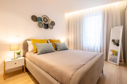 um quarto com uma cama grande com almofadas amarelas e azuis em Moliceiros Aveiro em Aveiro
