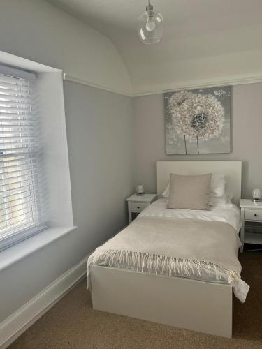 a white bedroom with a bed and a window at Beachglass in Lynton