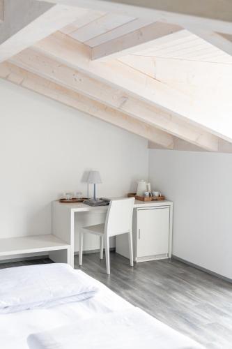 a white bedroom with a desk and a bed at Hotel Baia Azzurra - Lake Front in Nago-Torbole