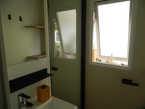 a bathroom with a mirror and a sink and a window at Charmant mobil home 331 camping 4* Siblu La Réserve in Gastes