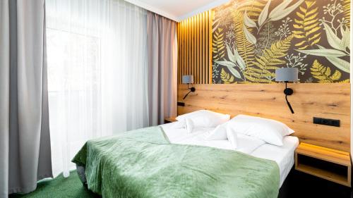 Apartamenty Sun & Snow Wczasowa 17 في شيراردوف ازدروي: غرفة نوم مع سرير مع لحاف أخضر