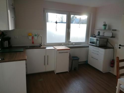 a kitchen with a sink and a microwave and two windows at Jana's Fewo in Lübeck