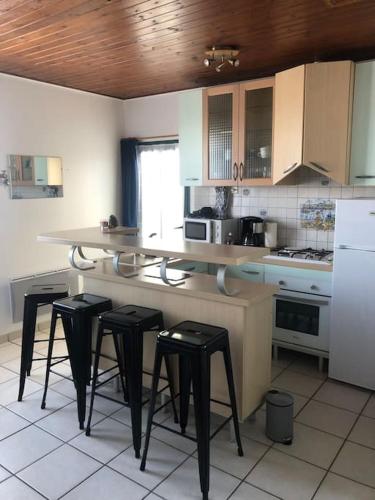 une cuisine avec un comptoir avec quatre tabourets dans l'établissement Appartement bord de mer, à La Tranche-sur-Mer
