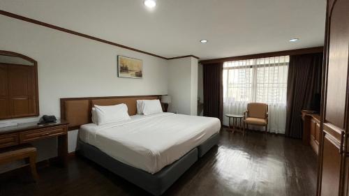 バンコクにあるイエロー リボン ヒルズ ブティック スイーツのベッド、デスク、窓が備わるホテルルームです。
