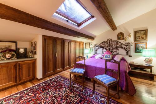 a bedroom with a bed with purple bedspread and two chairs at Residenza del Bravo by Mmega in Impruneta