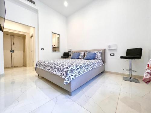 a white bedroom with a bed and a chair at SOLEIL LUXURY APARTMENT in Maiori