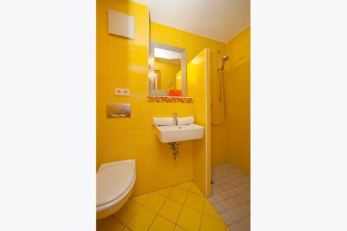 a yellow bathroom with a sink and a toilet at Landhaus Almdorf in Sankt Johann in Tirol