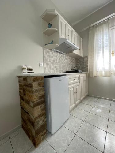 a kitchen with white cabinets and a white refrigerator at Manto Apartments in Tinos Town