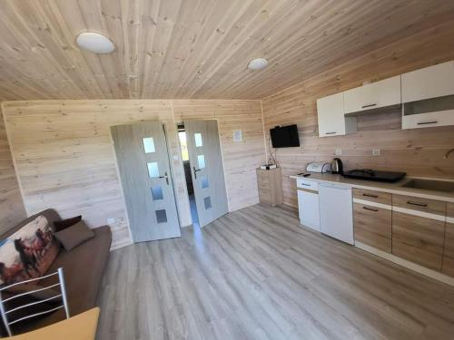 a large kitchen with wooden walls and wooden flooring at Bajkowe Chatki in Rusinowo