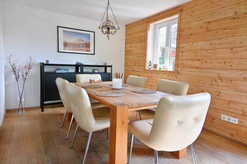 a dining room with a wooden table and white chairs at Traum Chalet mit Privatwald & Almhütte in Irdning