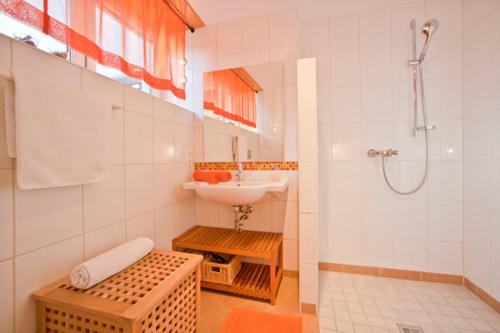 ein weißes Bad mit einem Waschbecken und einer Dusche in der Unterkunft Landhaus Almdorf in Sankt Johann in Tirol