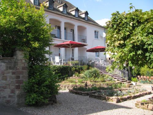 ein Gebäude mit Treppen und Sonnenschirmen in einem Garten in der Unterkunft Kräuterhotel Villa Vontenie in Kordel