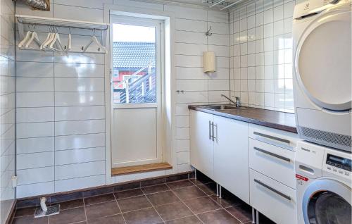 a kitchen with a washing machine and a window at Stunning Home In Hvik With Wifi 