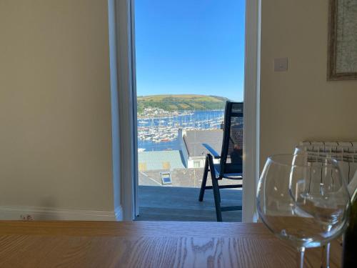 two wine glasses sitting on a table in front of a door at Chapel House - Stunning River Views, Sunny Balcony with Parking in Dartmouth