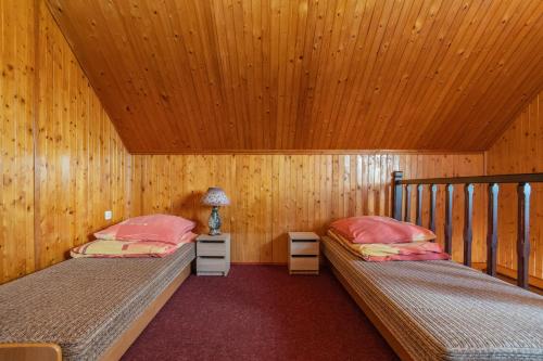 two beds in a room with wooden walls and wooden ceilings at Przestronne domki Sztutowo in Sztutowo