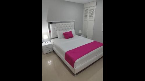 ein Schlafzimmer mit einem weißen Bett und einem rosa Kissen in der Unterkunft Bm-8 room near the sea with air conditioning and WIFI in Cartagena de Indias