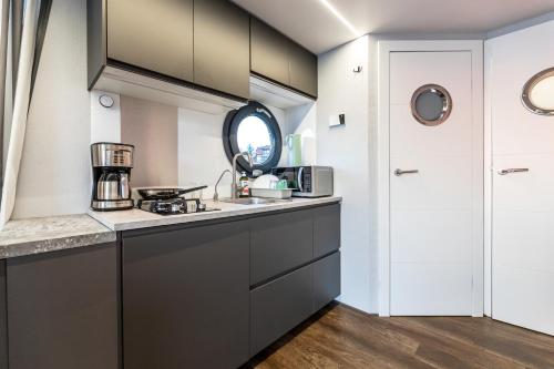 a kitchen with black cabinets and a sink at Domek na wodzie Topiko Czarter przy Hotelu Ognisty Ptak in Ogonki