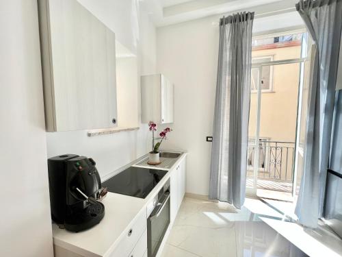een witte keuken met een wastafel en een raam bij LEI LUXURY APARTMENT in Maiori