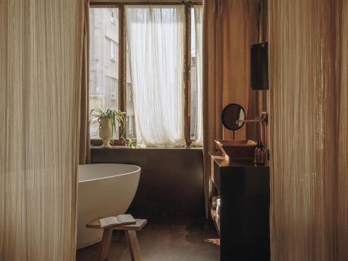 a bathroom with a white tub and a window at Mona Athens in Athens