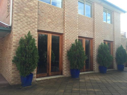 a brick building with three potted trees in front of it at Bright on Track in Bright