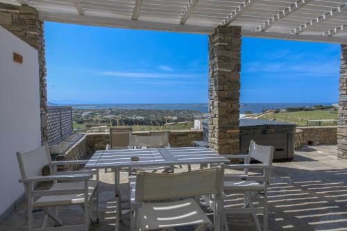 a table and chairs on a patio with a view of the ocean at Anthemion Paros - Villas & Suites in Agia Irini Paros