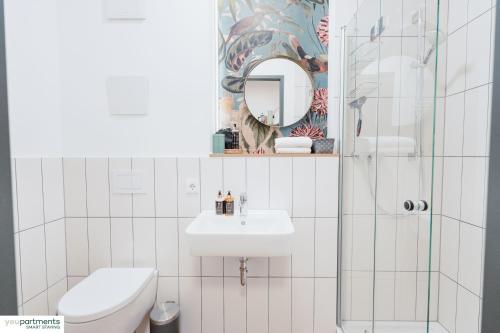 a bathroom with a sink and a toilet and a mirror at City-Studio mit Boxspring-Bett und Küche in Münster