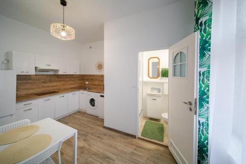 - une cuisine avec des placards blancs, une table et un évier dans l'établissement Jungle Vision Apartment - Rynek, à Carolinensiel