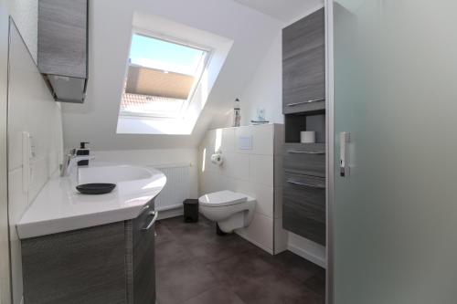 uma casa de banho com um lavatório branco e um WC. em Ferienwohnungen Gatena em Norddeich
