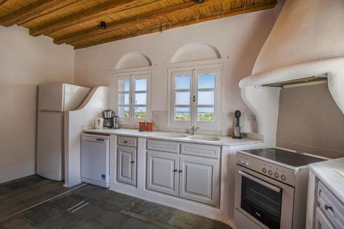 a kitchen with white cabinets and a refrigerator at Anthemion Paros - Villas & Suites in Agia Irini Paros