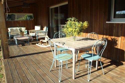 une table et des chaises en bois sur une terrasse dans l'établissement Wooden house by the sea, à Hourtin