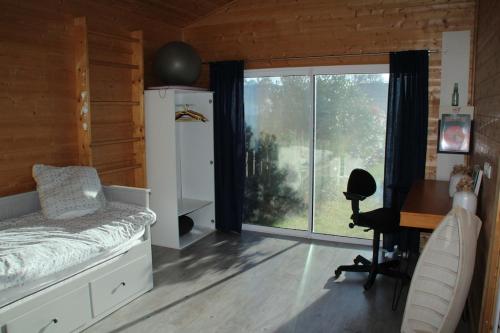 a bedroom with a bed and a desk and a window at Wooden house by the sea in Hourtin