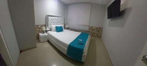 a small bedroom with a bed with a blue blanket at Bm-3 room near the sea with air conditioning and WIFI in Cartagena de Indias