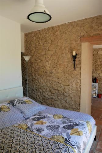 une chambre avec un lit et un mur en pierre dans l'établissement L'Ermitage, à Betcave-Aguin