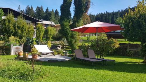 a patio with two chairs and an umbrella in a yard at Landhaus Almdorf in Sankt Johann in Tirol