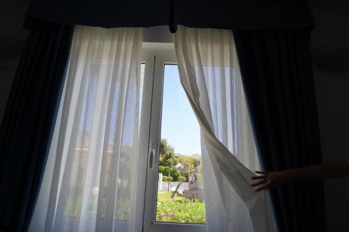 a person is looking out of a window at Hotel Parco Delle Agavi in Ischia