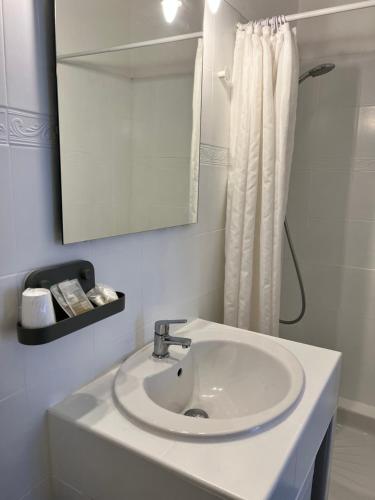W białej łazience znajduje się umywalka i lustro. w obiekcie Les Enfants Terribles w mieście Villeneuve-lès-Béziers
