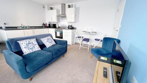 a living room with a blue couch and a kitchen at Friars House, Stafford by BELL Apartments in Stafford