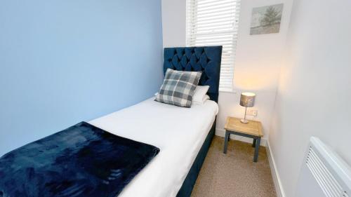 a small bedroom with a bed and a side table at Friars House, Stafford by BELL Apartments in Stafford
