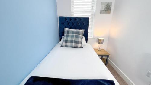 a white bed with a blue headboard in a bedroom at Friars House, Stafford by BELL Apartments in Stafford