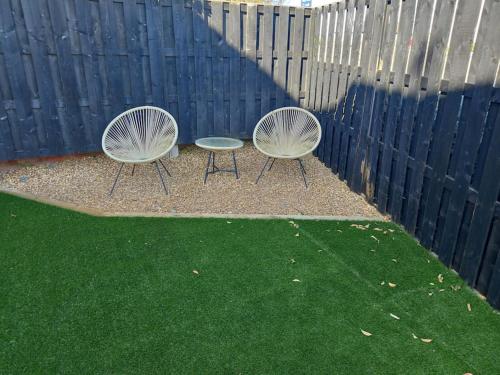 two chairs and a table in front of a fence at Amazing Beach House, Sleeps 8, Pet Friendly in Trearddur