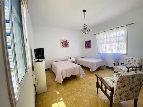 a room with two beds and a chair and a window at Lightbooking Hermigua vista al mar y al Teide in Hermigua